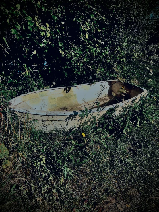 a rowboat lies on the grass next to water