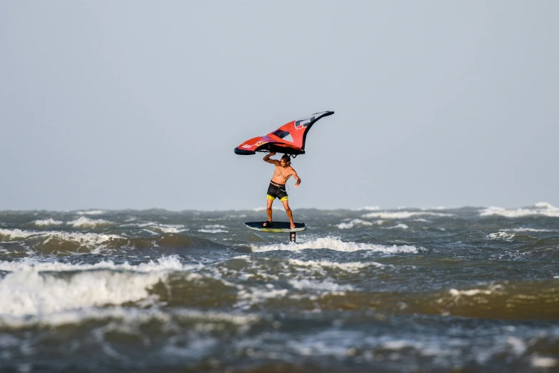 a man is standing on his surf board with a life jacket on