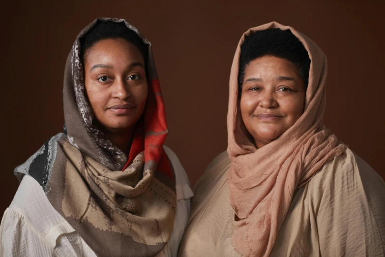 two women standing side by side wearing headscarves
