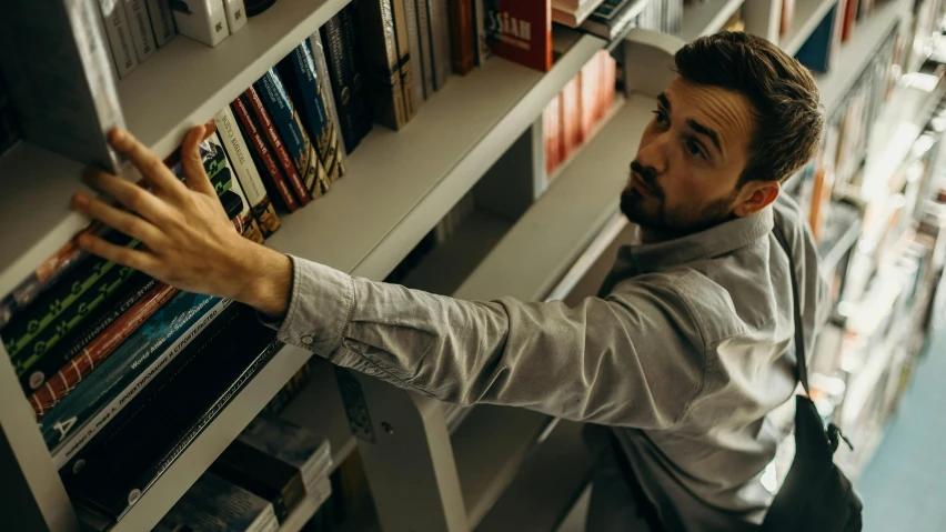 a man in the liry reaching for books