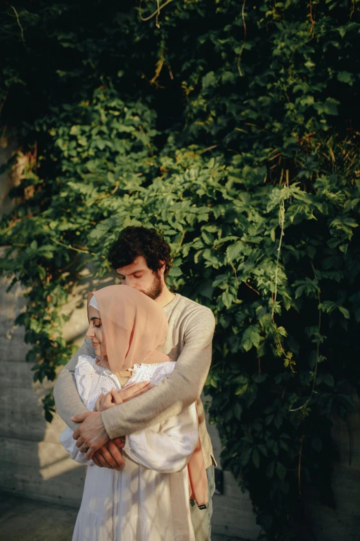 man and woman hug in front of ivy covered wall