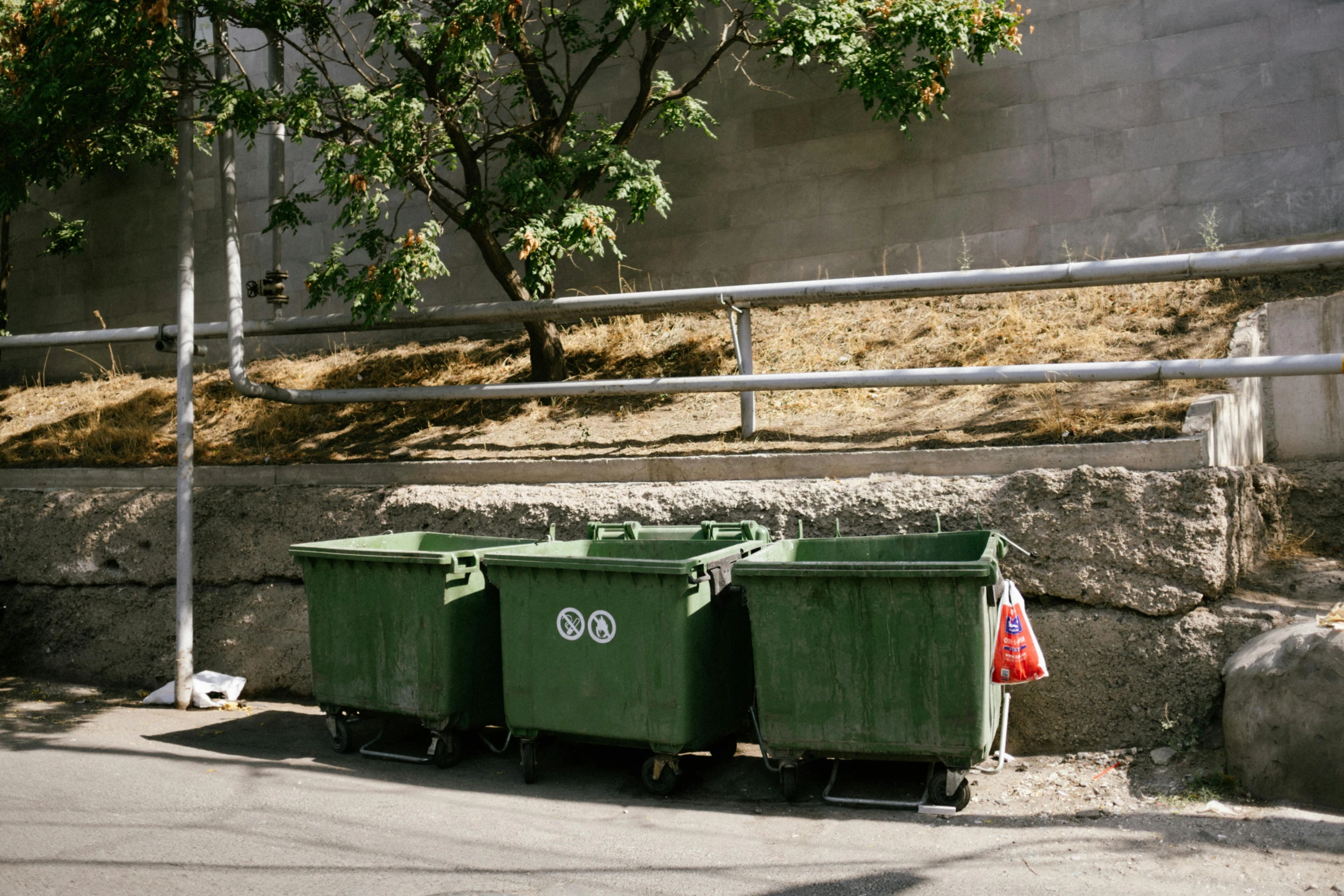 green containers and a red bag are by the side of a road