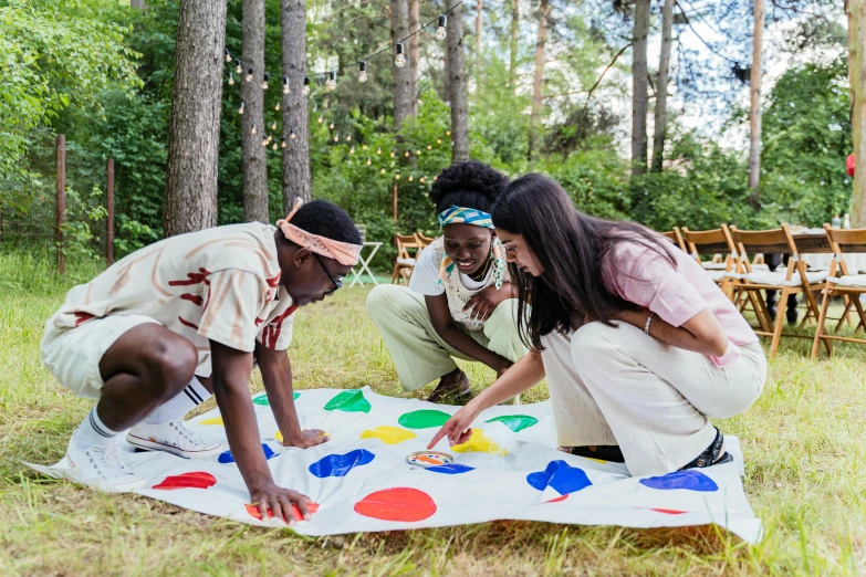 three people painting on a large blanket in the woods