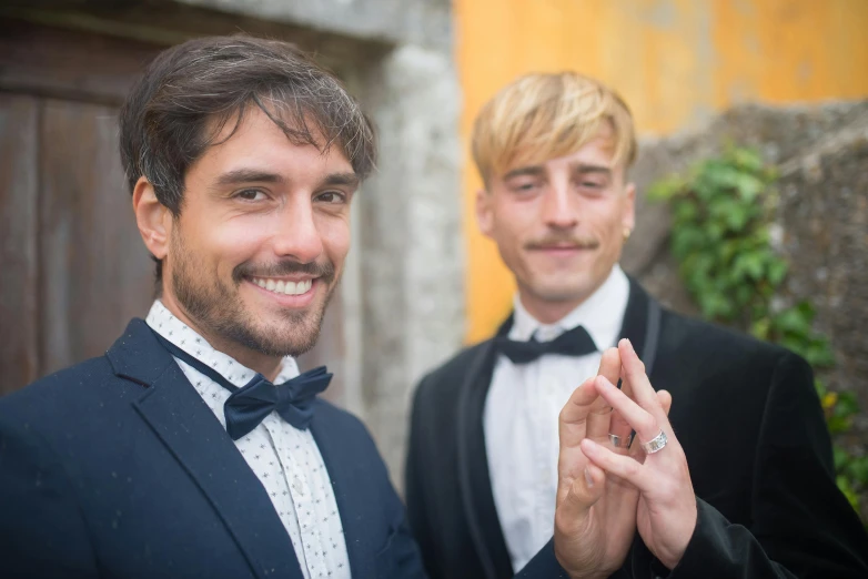 two men with suits and bow ties are smiling