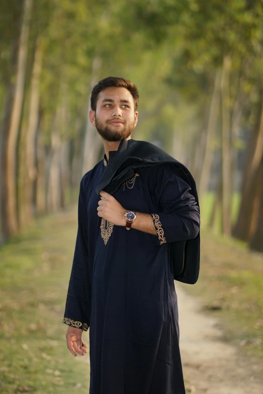 a man with his arms crossed on a path near trees