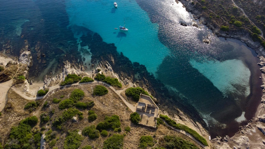 an aerial view of a small island with some boats floating on the water