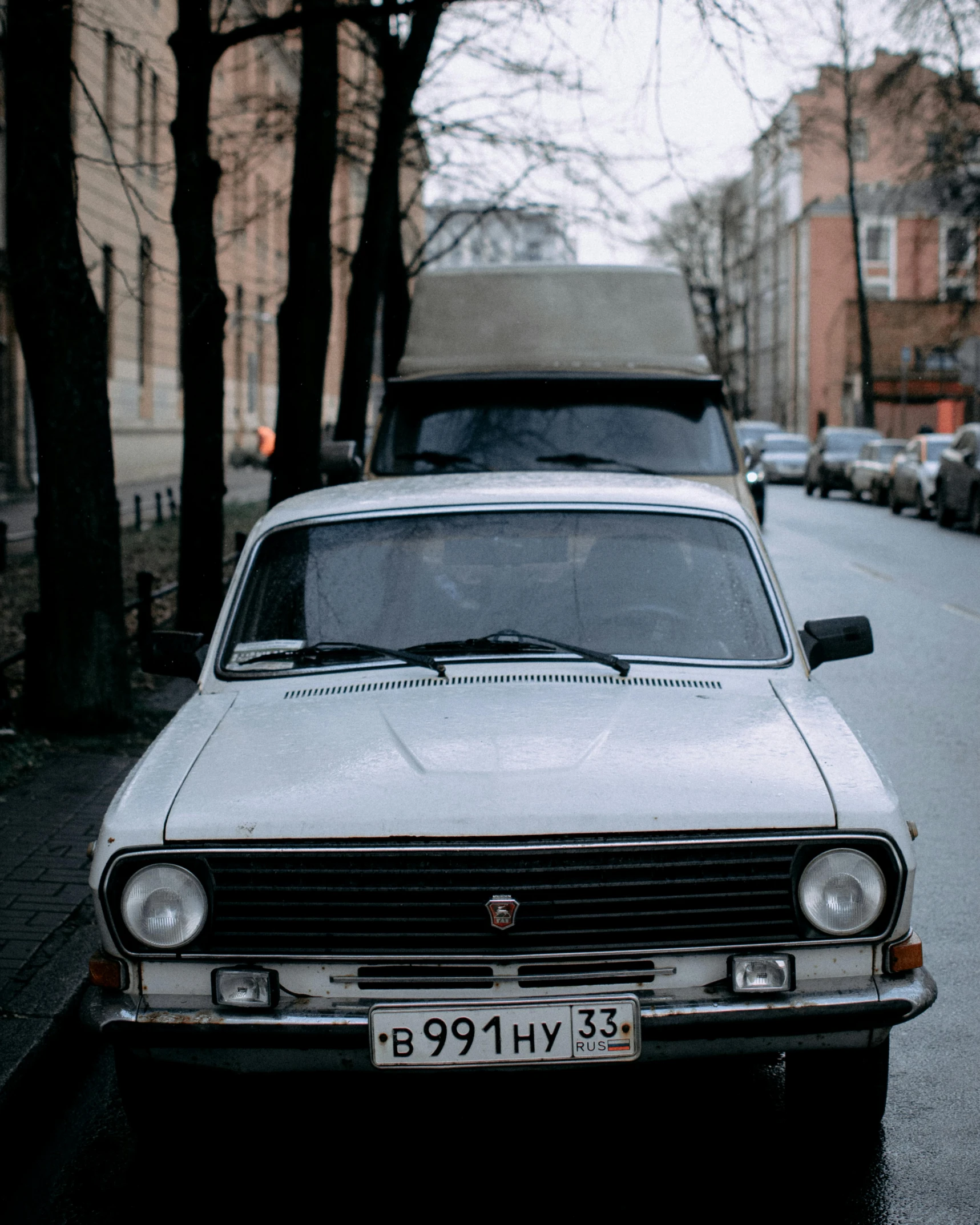 an old car with the hood off parked on the street