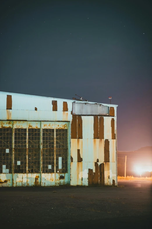 an abandoned rusty building is standing on a dirt lot