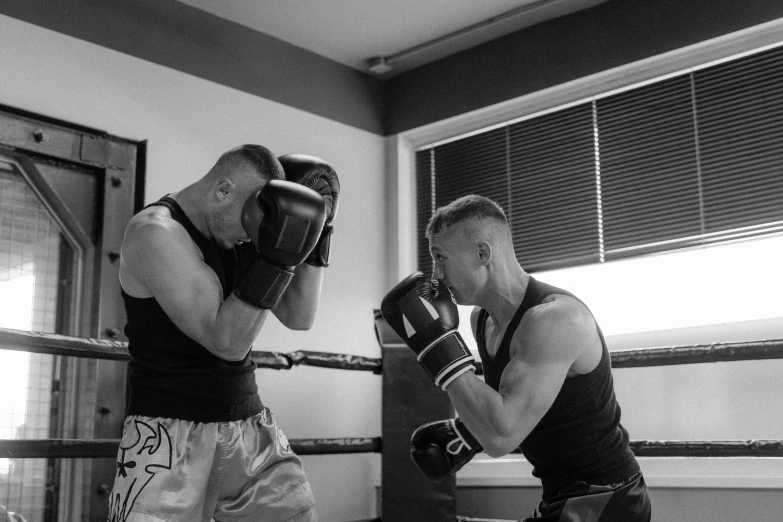 two men in boxing gloves and with one of the hands on a rope