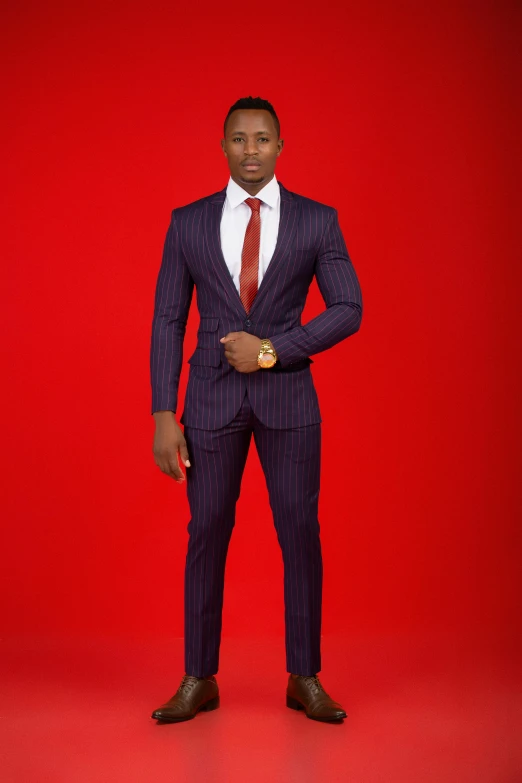 a young man dressed in a suit with a red background