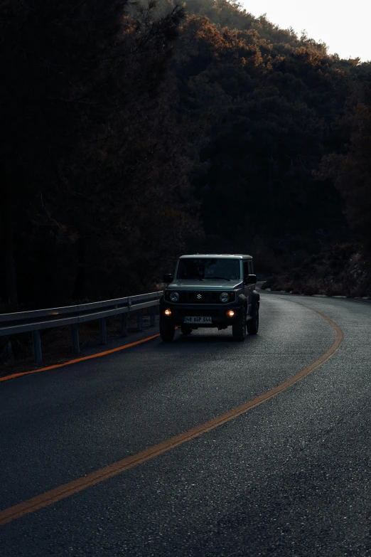 black jeep with headlights driving down a mountain road