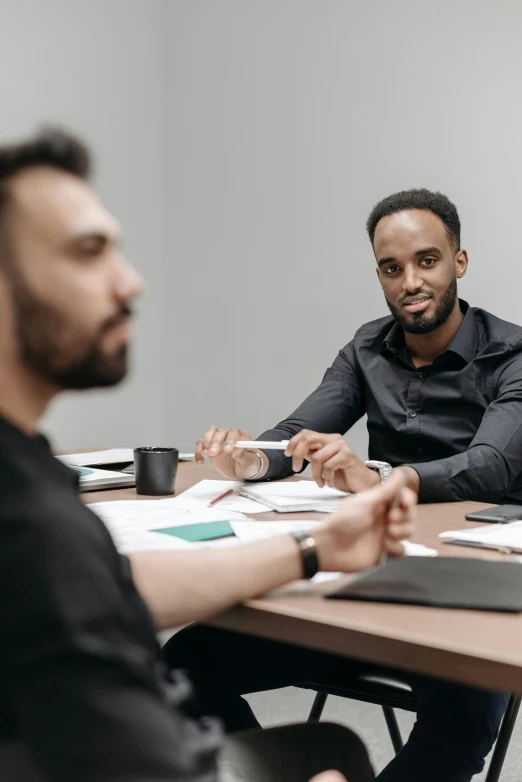 two men at tables with papers on one