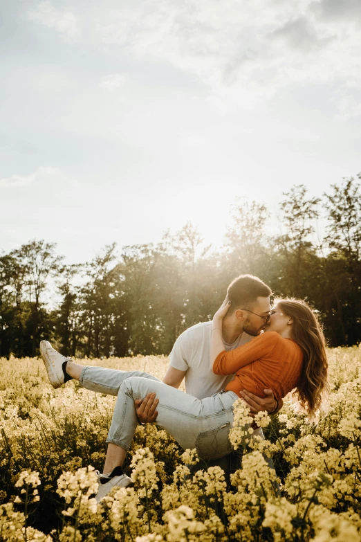 two people are in a field of flowers as the sun shines