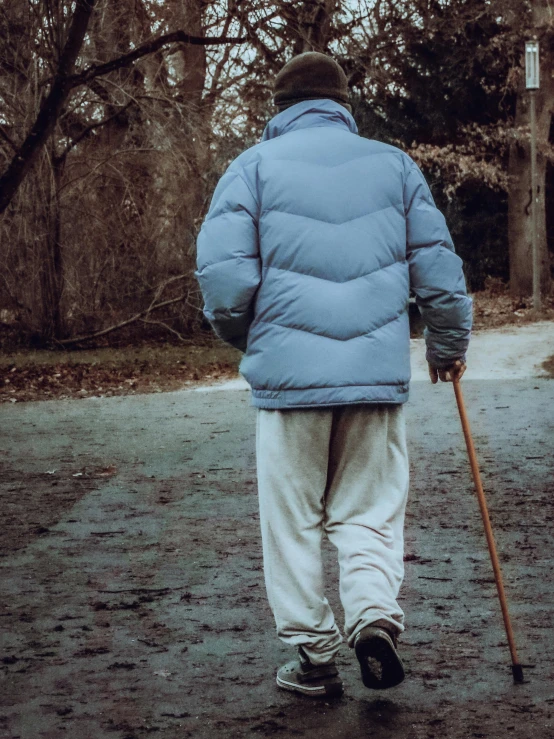 a man walks on the road with a cane