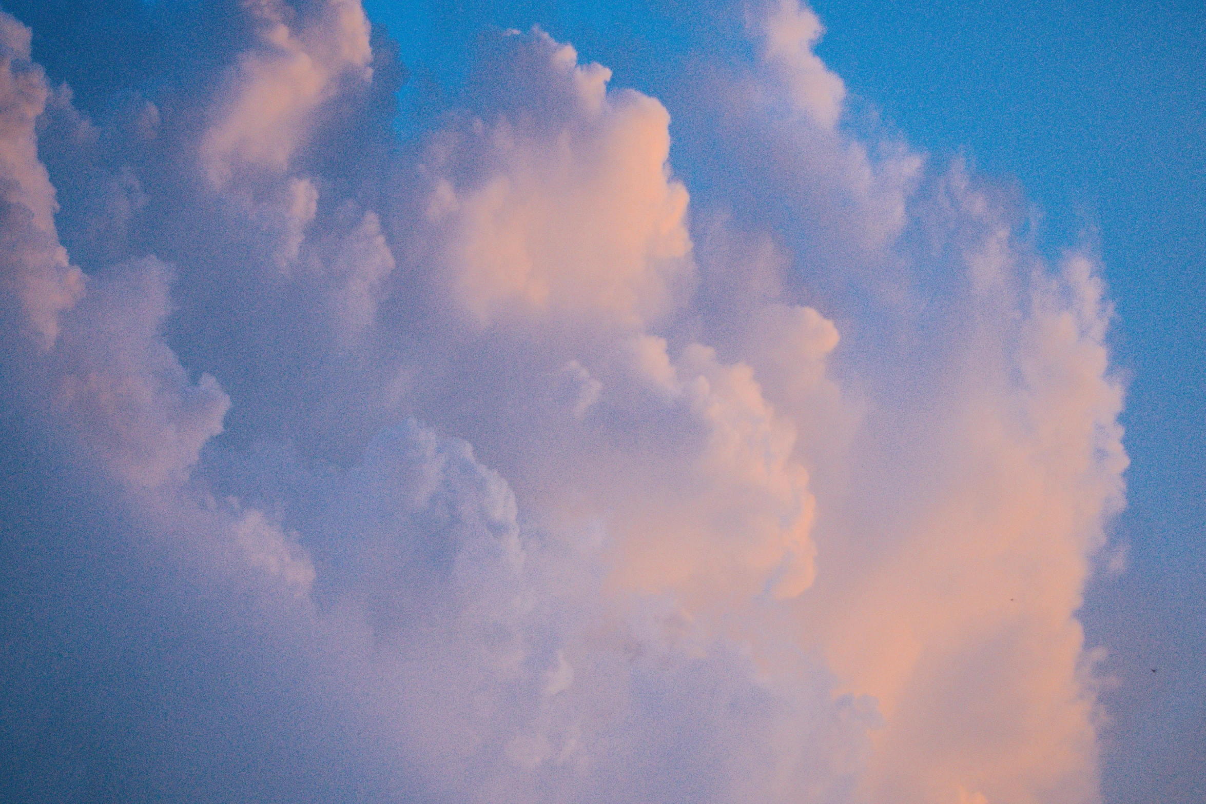 clouds are floating high in the sky above a street light