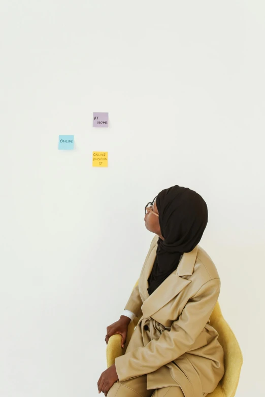 a woman in a yellow chair looks at sticky notes