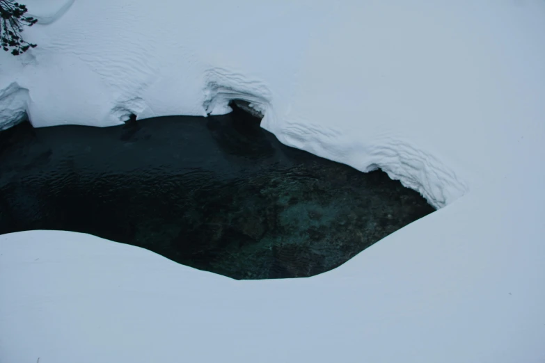 a very dark pond near some snowy rocks