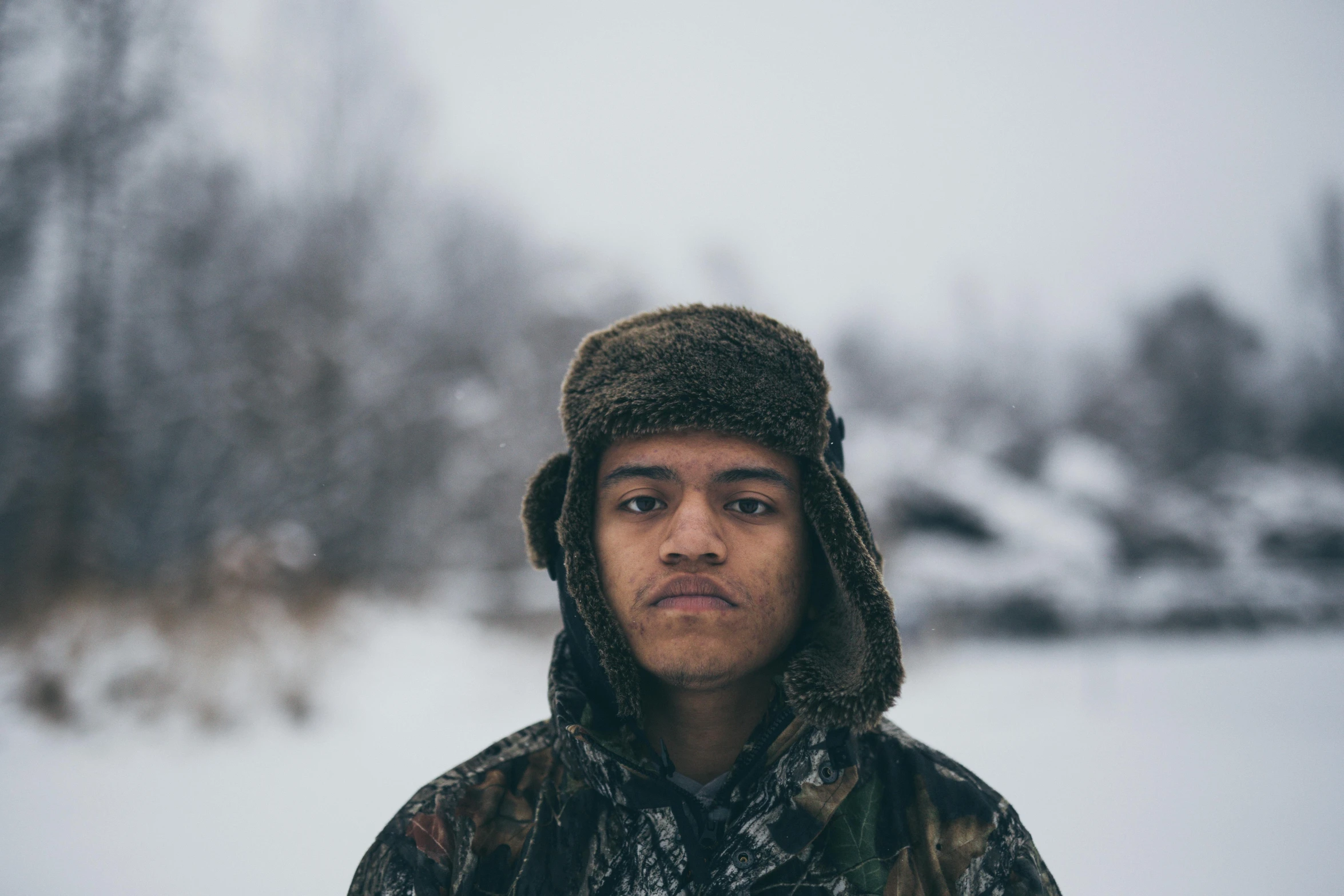 a young man with hood and a fur cap in winter time