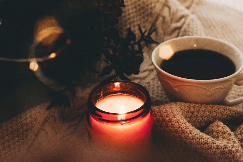 a candle next to a cup and some coffee