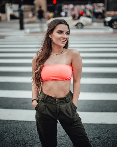a young woman standing on the side of the road in an orange top