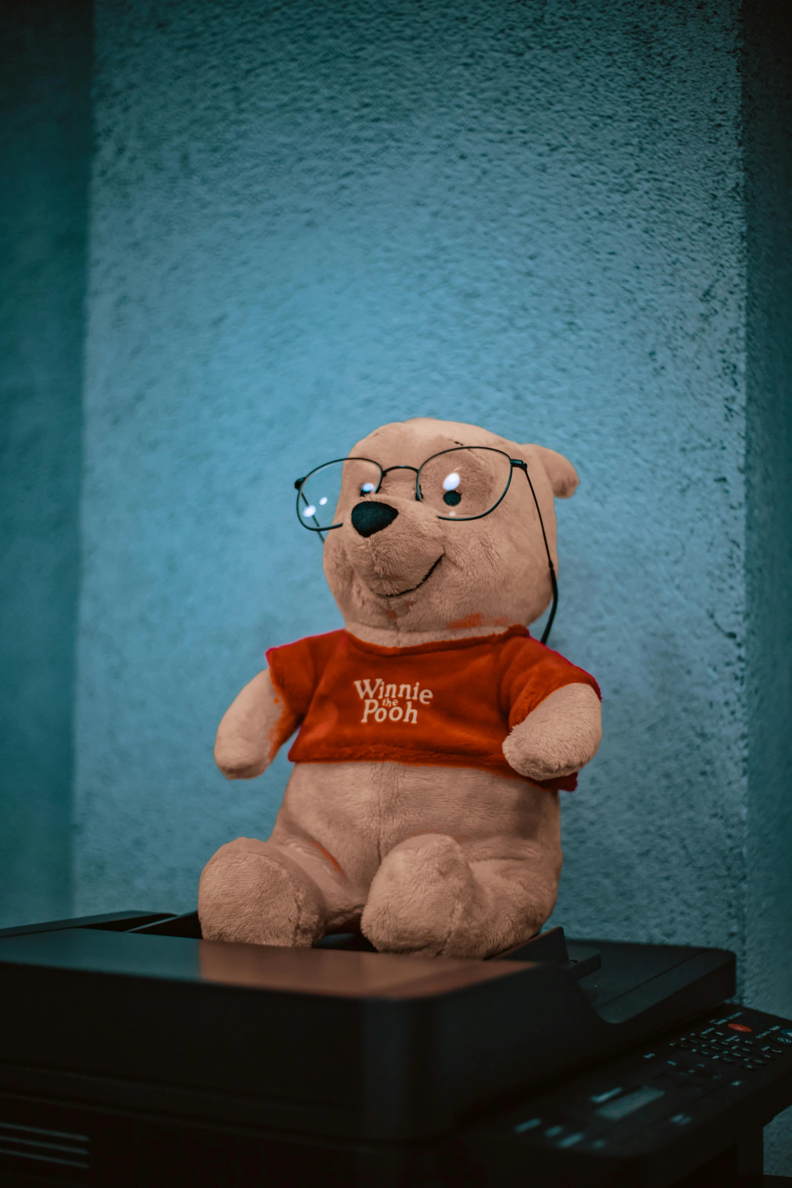 a light brown teddy bear wearing a red shirt and glasses