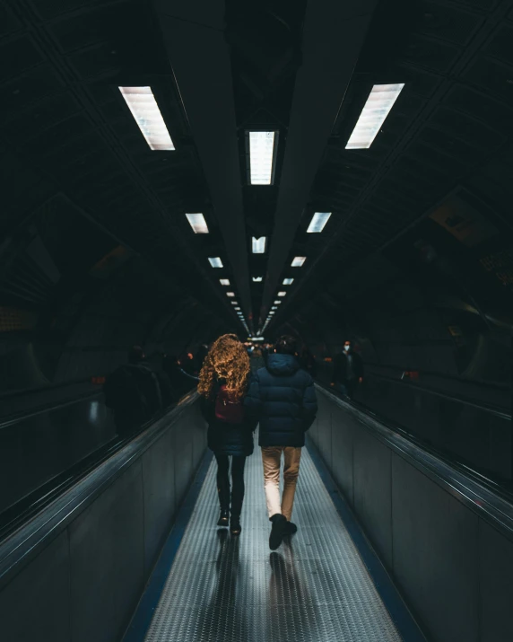 two young women walking down a subway tunnel