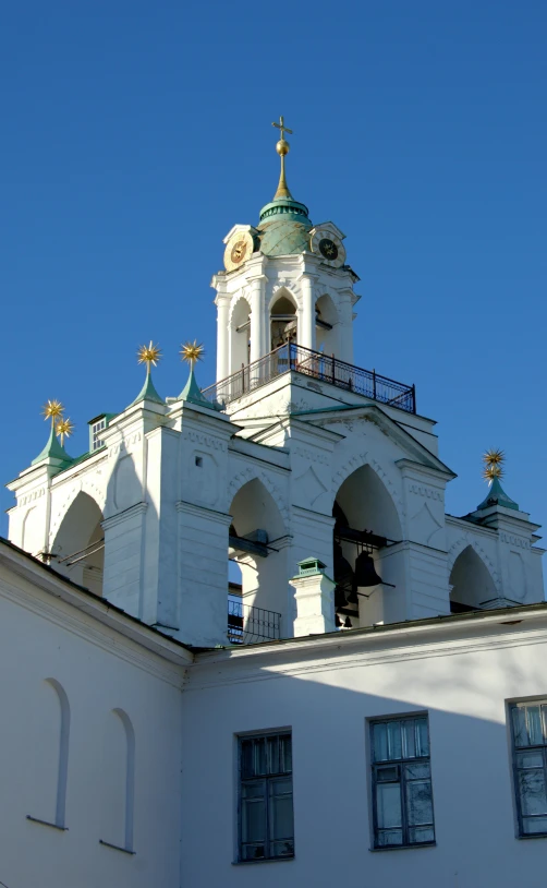 an elaborate white building with gold roof and bell tops