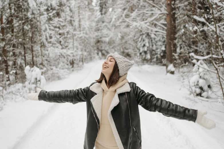 a woman with her arms outstretched in front of the snow covered forest