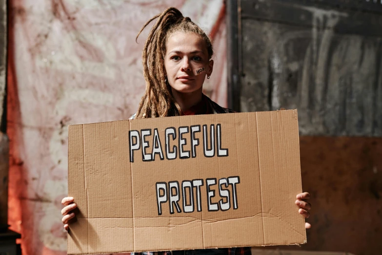 a woman holding a cardboard sign reading peaceful protest