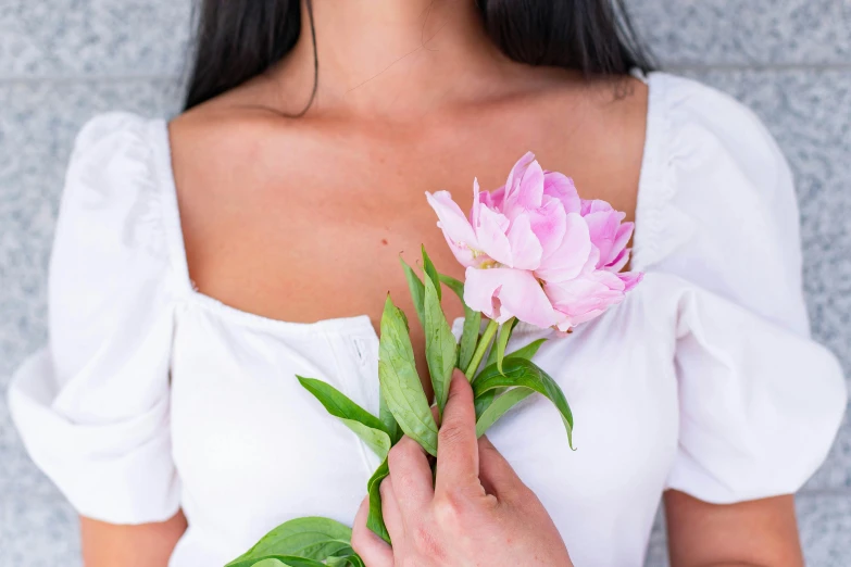 a woman holds up a flower in her right hand