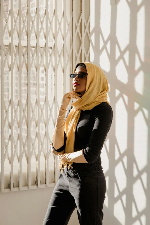 a woman is standing next to a window wearing a scarf