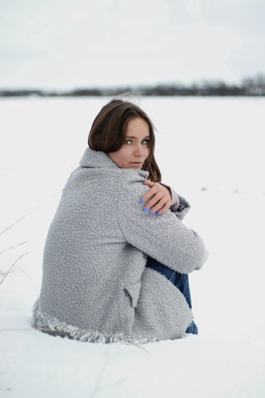 a woman sits in the snow with her arms crossed