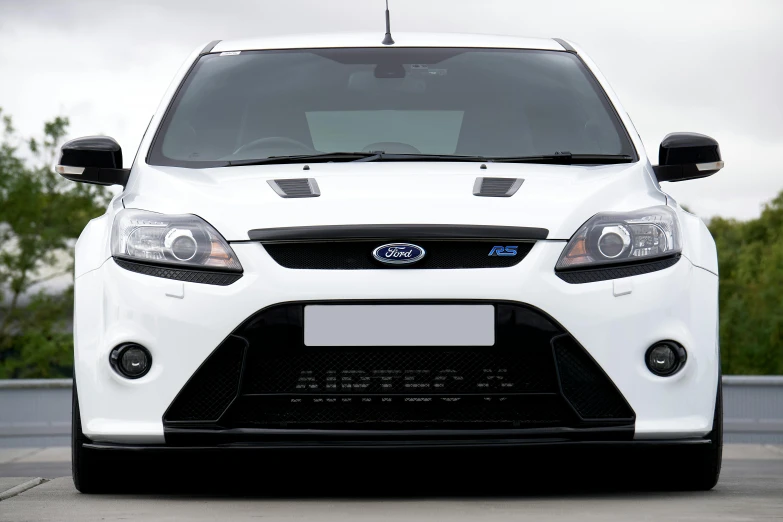 the front end of a white focus focus parked on a concrete surface