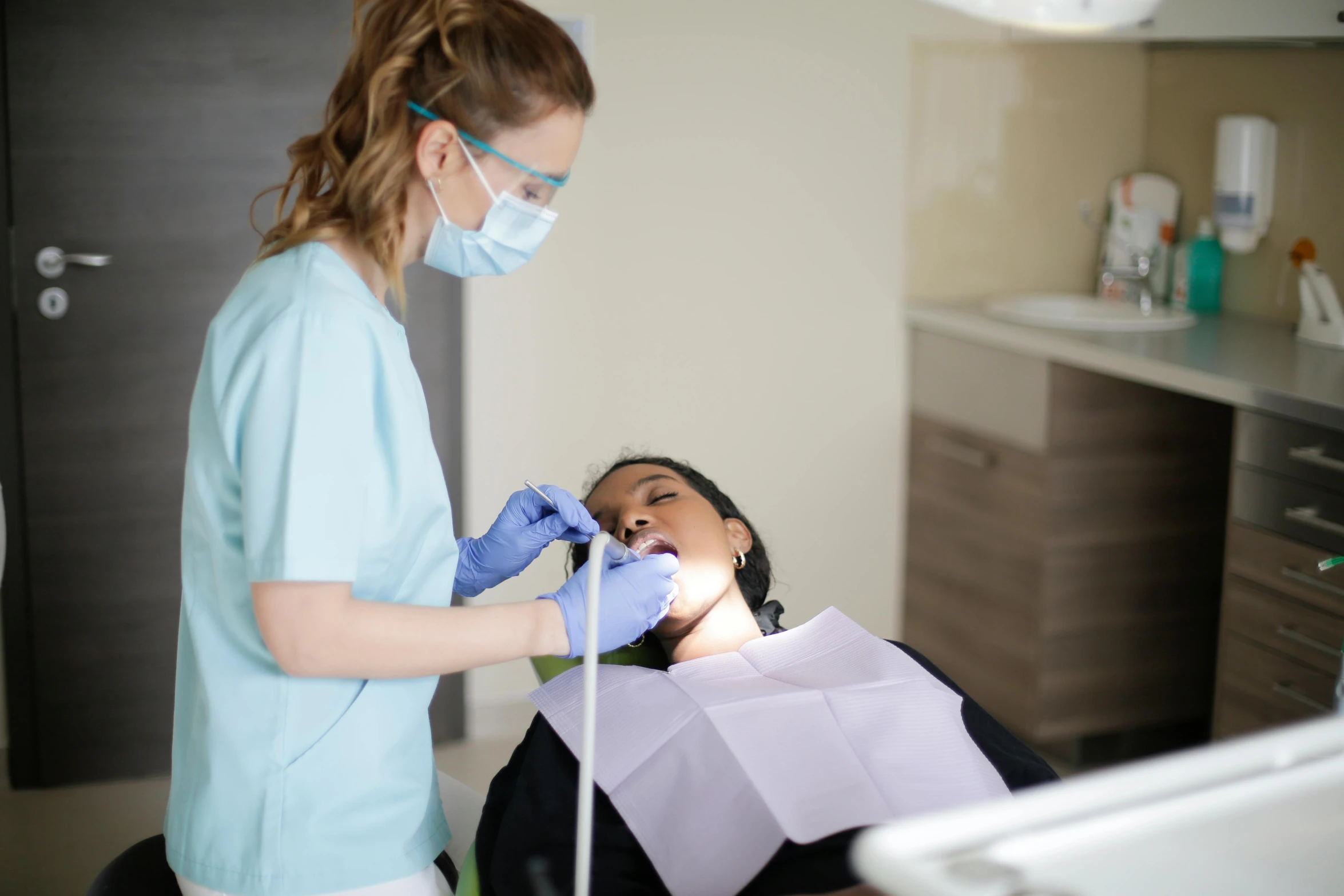 an asian woman gets a tooth check from a dentist