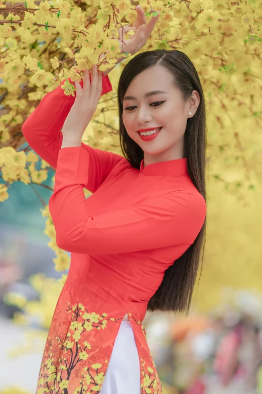 an oriental woman holding a yellow umbrella under trees