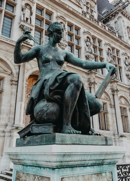 a statue of a woman with a bagpipe sits in front of an old building