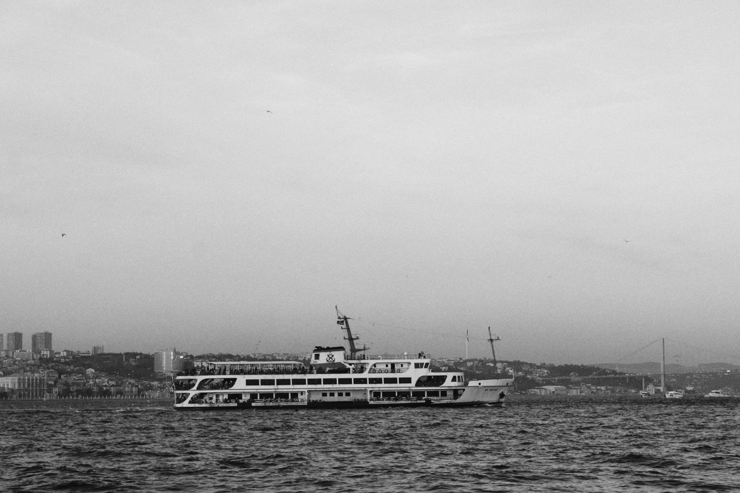 large ship sailing out on calm water in black and white