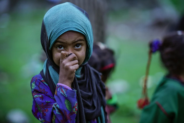 a little girl in a blue and green headscarf