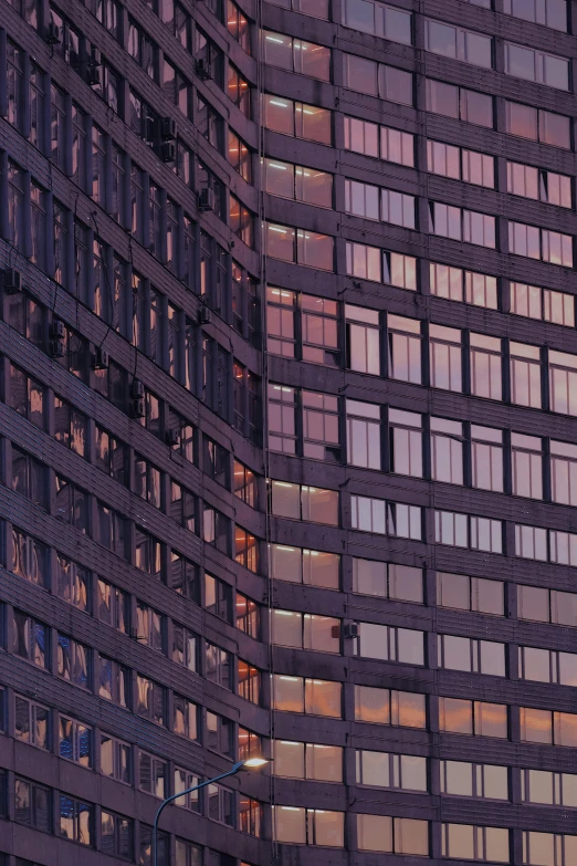 the tall windows in the office building are lit up