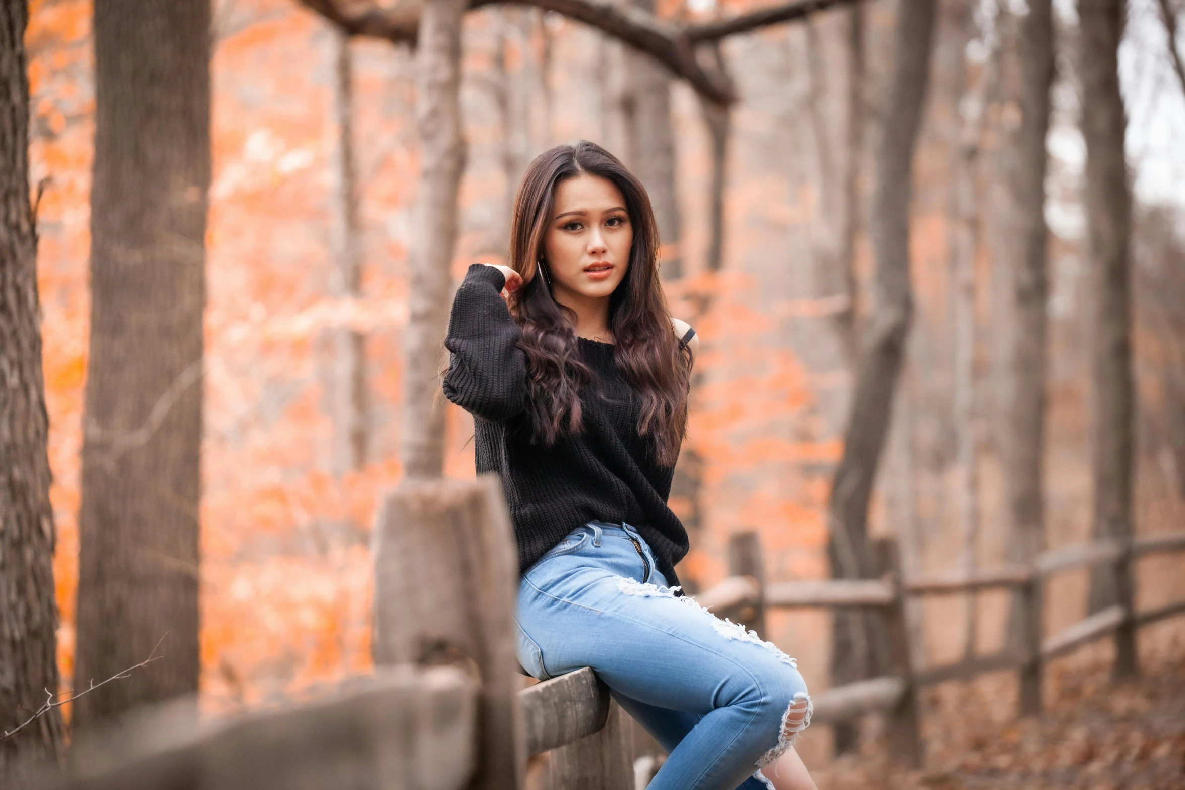 a girl leaning on a rail in the woods