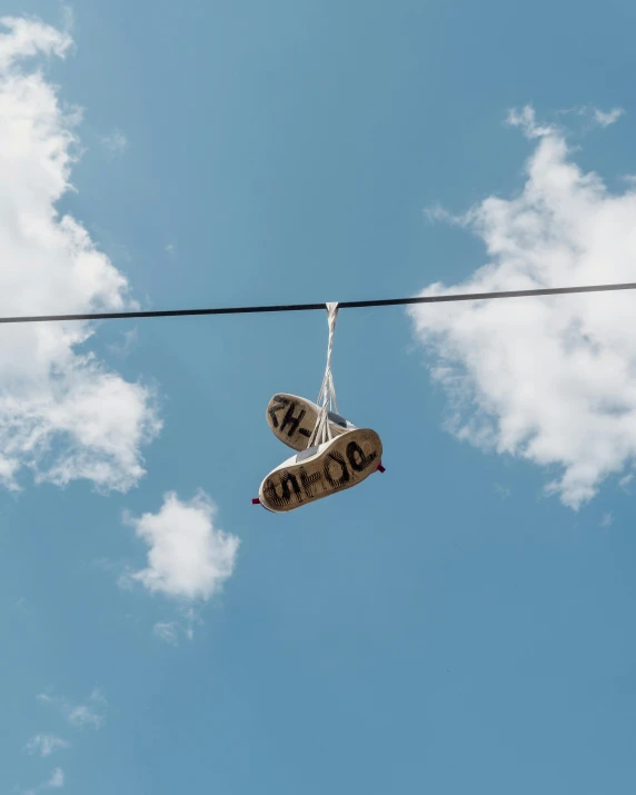 the pair of sneakers hanging on a wire has letters painted on them