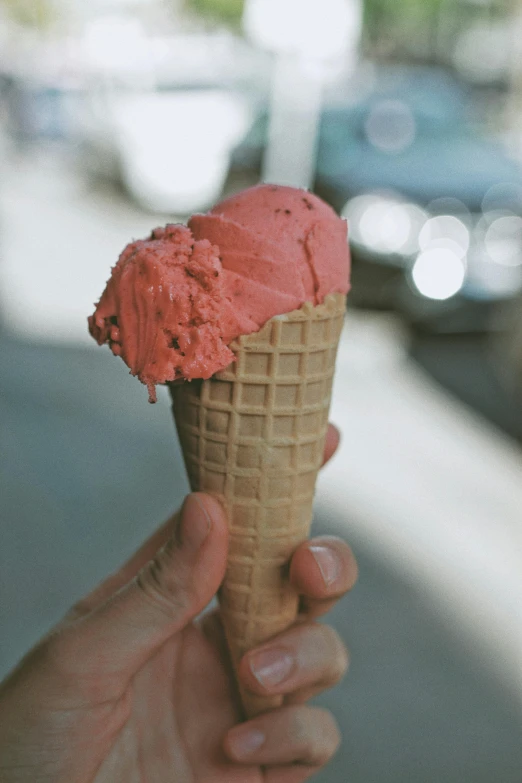 someone holding up an ice cream cone with red topping