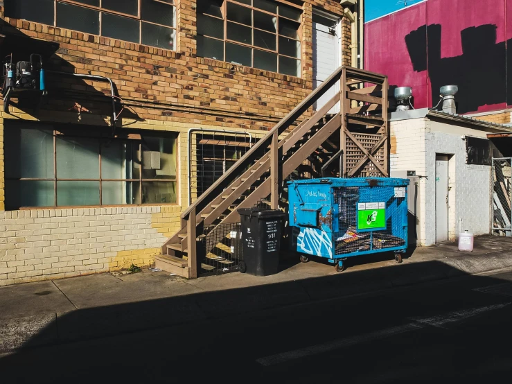 an urban area with stairs, two balconies and a blue trash can