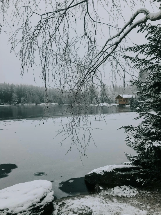 a frozen river with snow on it and a house in the distance