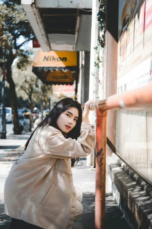 woman leaning against sign outside on sidewalk near sidewalk