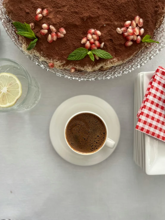 a cake next to cup of coffee on top of a table