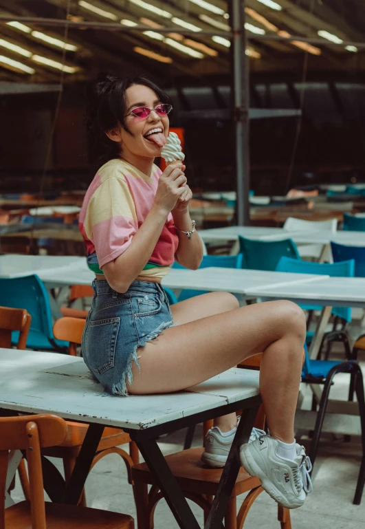 a woman wearing ripped shorts and sunglasses eating food