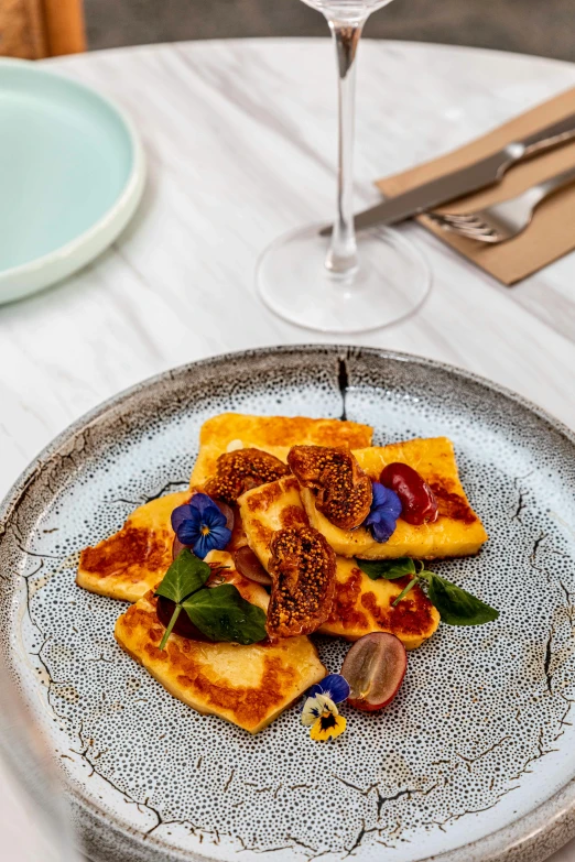 a plate of food next to a glass of wine on a table