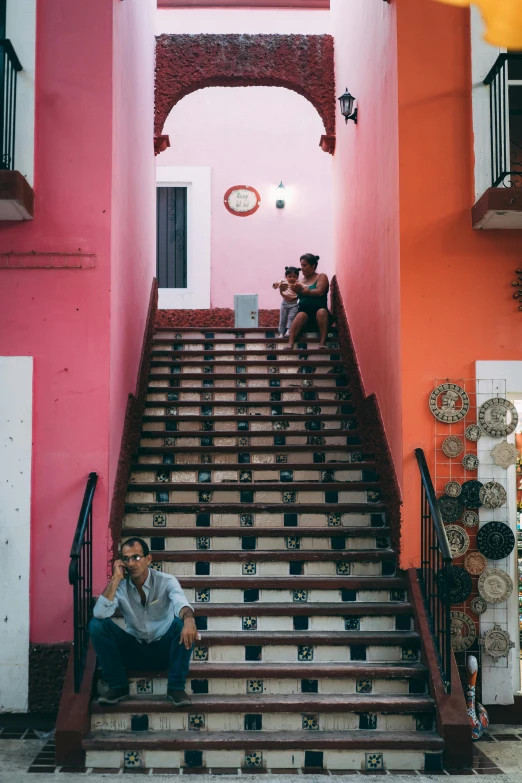 two men sitting on steps in front of a bright colored building