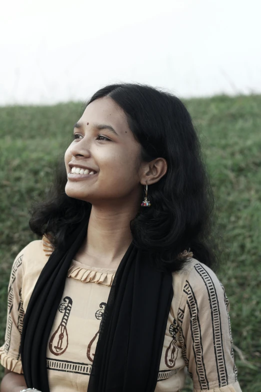 a woman wearing a scarf with some grass in the background